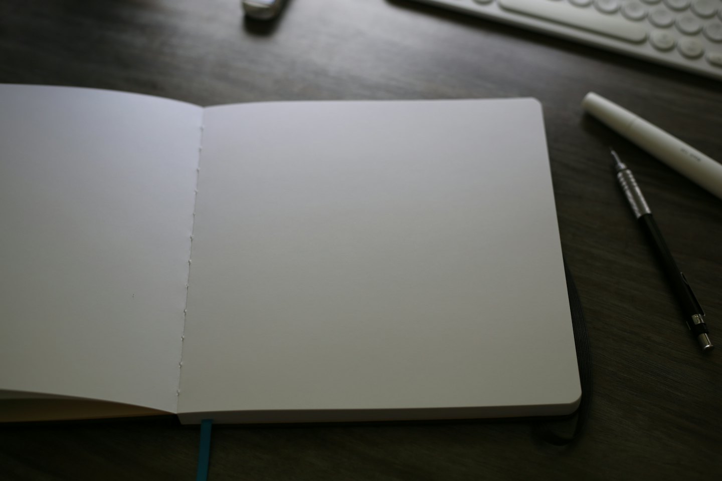 An open notebook with writing tools sits on a desk.