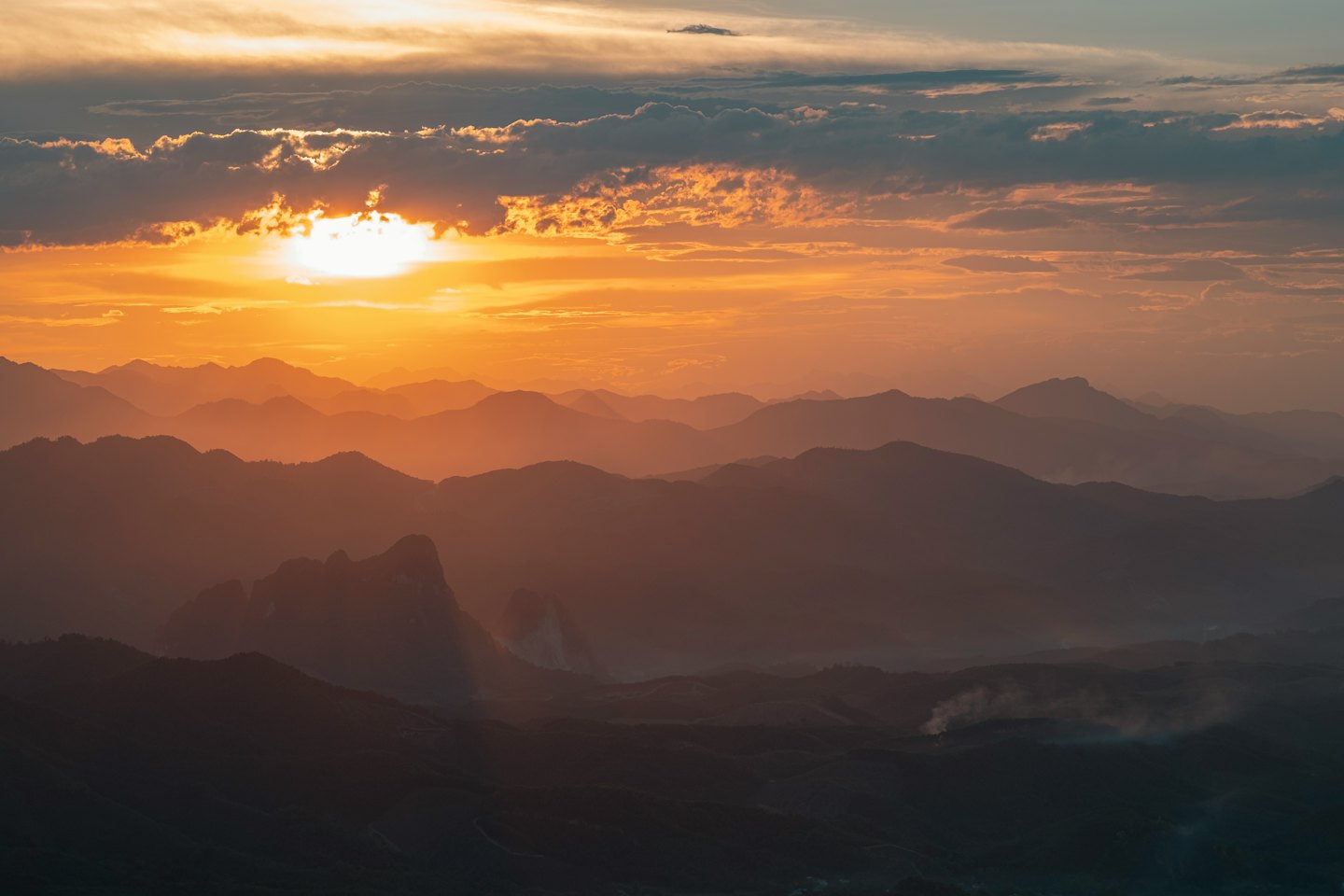 Layers of mountain ridges silhouette against a sunset sky.